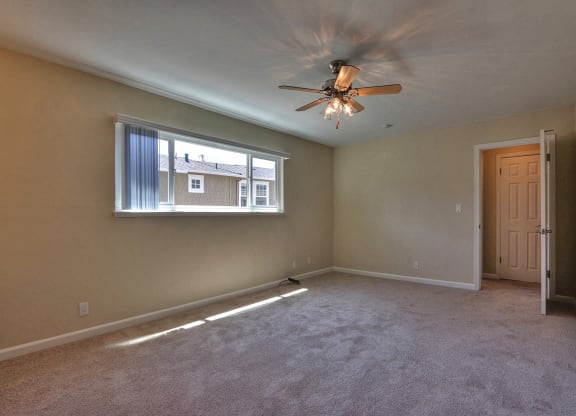 an empty living room with a ceiling fan and a window