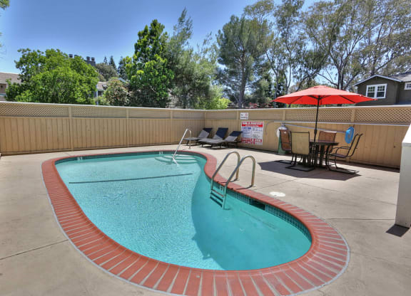 a swimming pool in a patio with chairs and an umbrella
