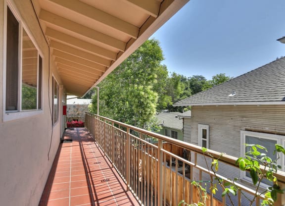 a balcony with a wooden railing and a house in the background