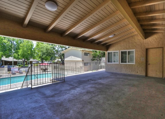 A covered patio area with a pool and a fence.