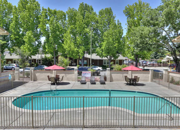 A pool surrounded by a fence with trees in the background.