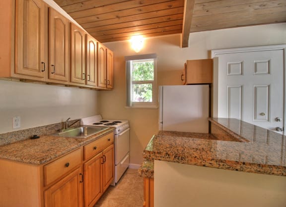 A kitchen with granite countertops and wooden cabinets.