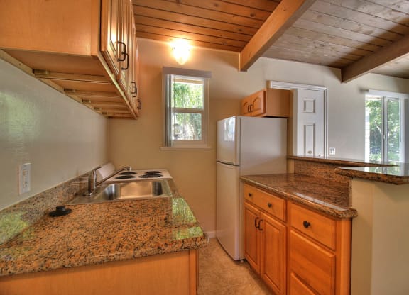 A kitchen with granite countertops and wooden cabinets.