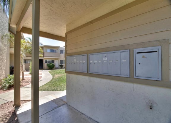 A row of mailboxes on a wall outside a building.