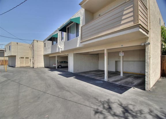 A parking lot in front of a building with a car parked.