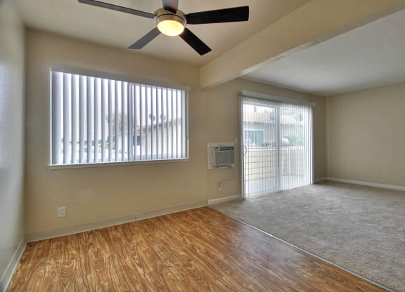 an empty living room with a ceiling fan and a window