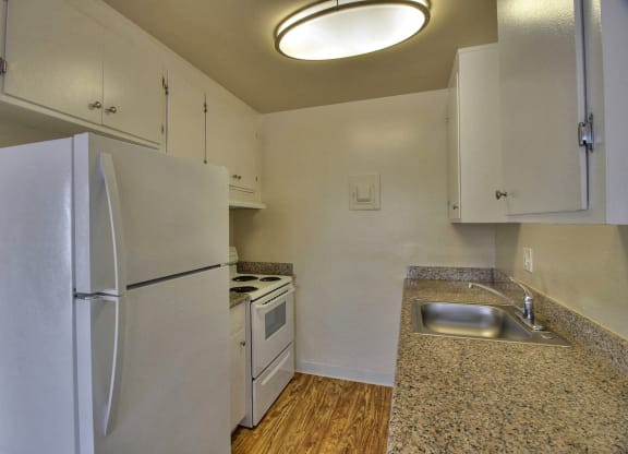 a kitchen with white appliances and a sink and a refrigerator