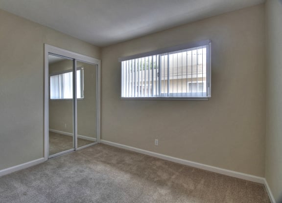 an empty bedroom with a window and a door to a closet