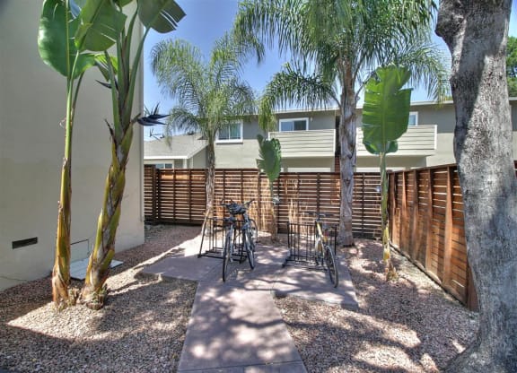 a patio with chairs and trees in front of a house