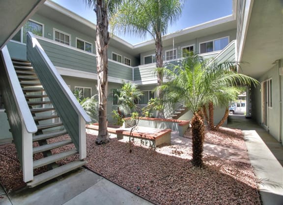 A patio with a bench and a tree in front of a building.