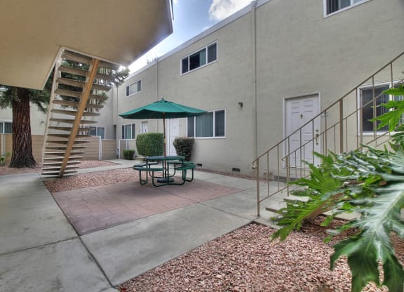 A patio with a table and chairs and a green umbrella.