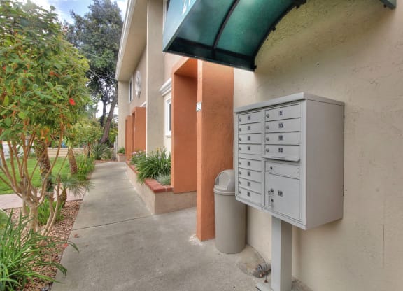 A grey mailbox is on the side of a building with a green awning.