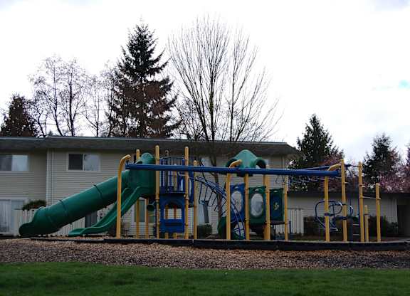 A playground with a green slide and a blue and yellow structure.