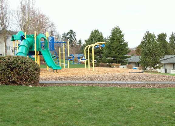 A playground with a green slide and yellow poles.