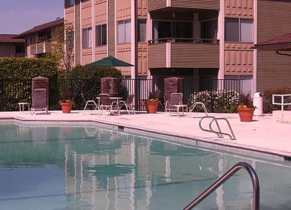 A pool in front of a building with a green umbrella.