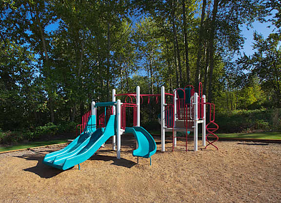 A playground with a red and blue slide and a red and white climbing frame.