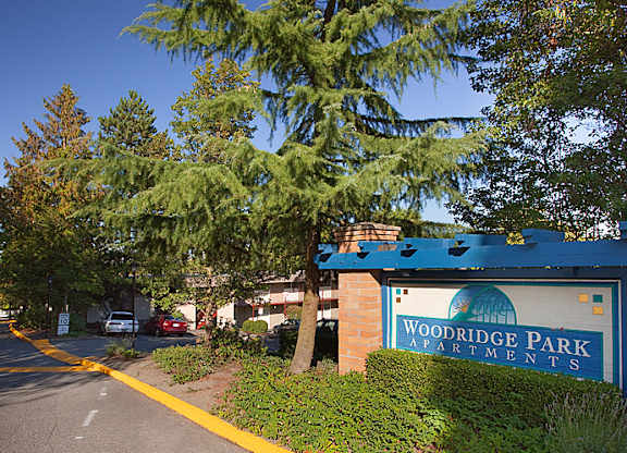 A sign for Woodridge Park Apartments is on the side of a street.