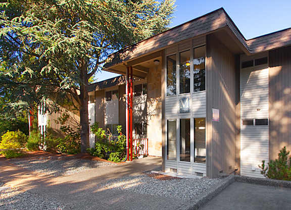 A modern house with a grey exterior and a red door.