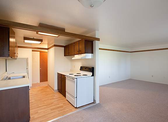 A kitchen with a white stove and wooden floors.
