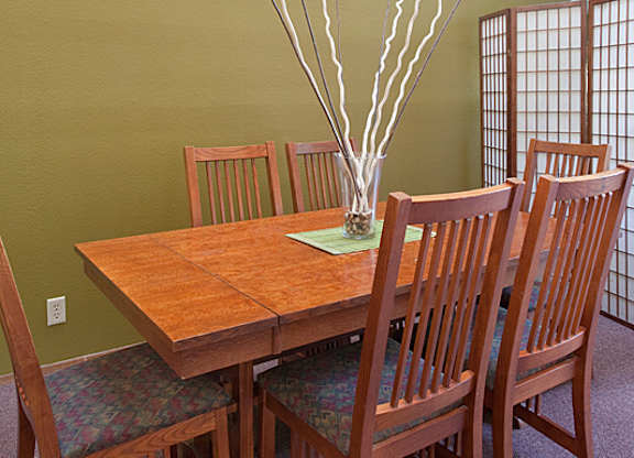 A wooden table with chairs and a vase with branches in it.