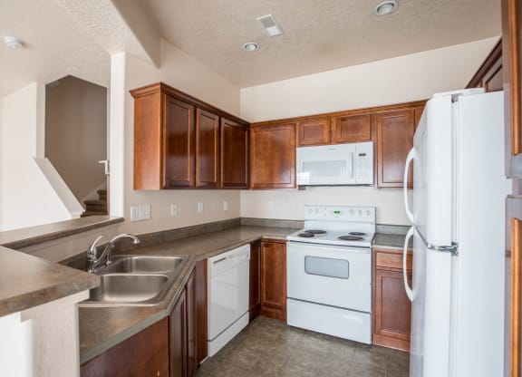 A kitchen with white appliances and brown cabinets.