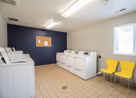 A laundry room with washing machines and dryers.