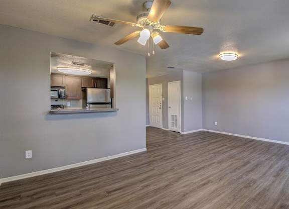 A room with a ceiling fan and wooden flooring.