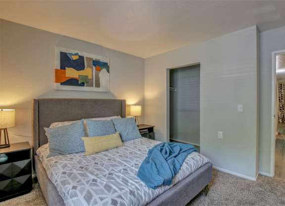 A bedroom with a bed, nightstands, and a painting on the wall.