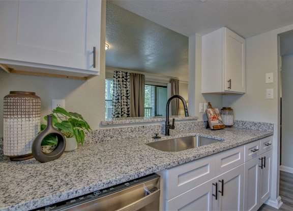 A kitchen with a granite countertop and white cabinets.