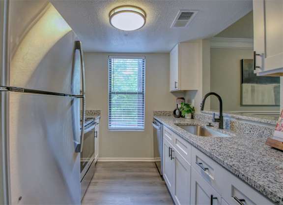 A kitchen with a refrigerator, sink, and cabinets.