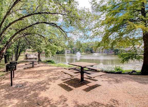 A picnic table is in the middle of a dirt area with a mailbox to the left and a tree to the right.