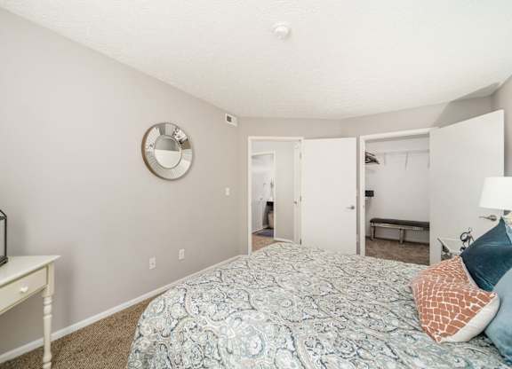 A bedroom with a bed, a mirror, and a lantern on a table.