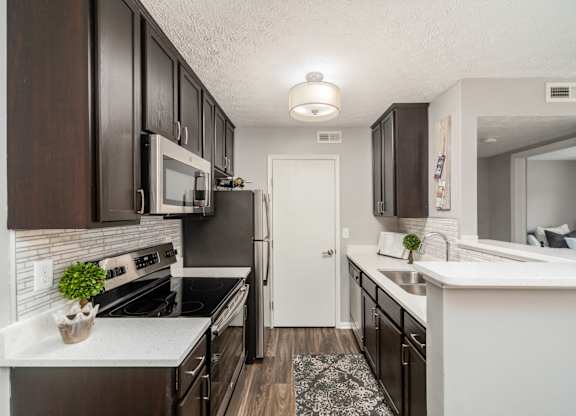 A kitchen with dark brown cabinets and white countertops.