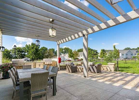 A patio with a table and chairs under a white pergola.