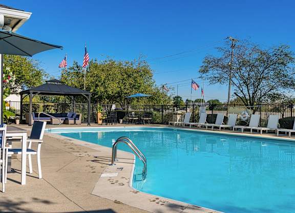 A pool with a slide and chairs around it.