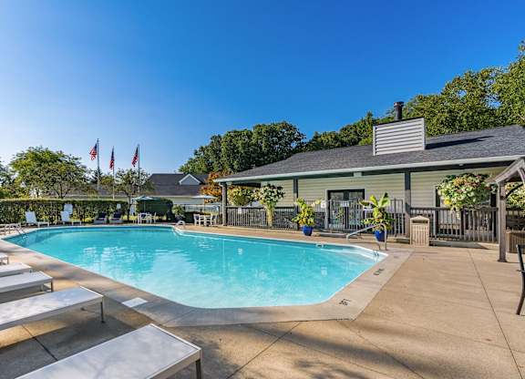 A pool with sun loungers and a building in the background.
