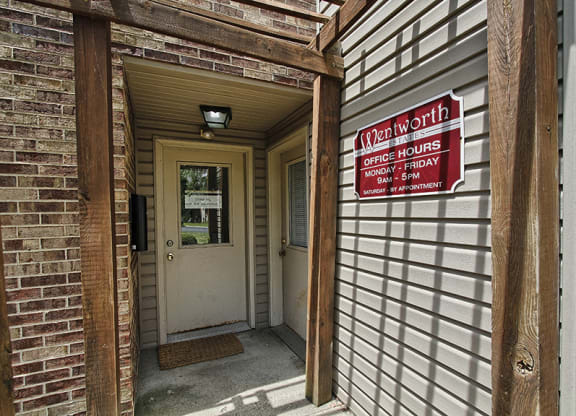 the front door of a brick building with a red and white sign at at Wentworth Estates Apartments, Florence, KY, 41042