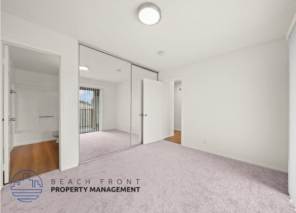 A spacious room with a carpeted floor and a sliding glass door leading to a balcony.