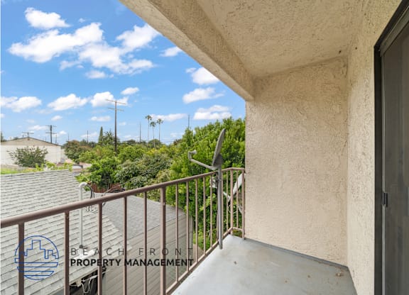 A balcony with a metal railing and a view of the sky and trees.