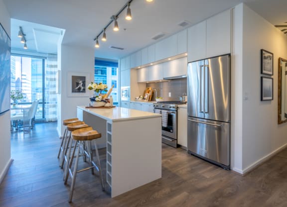 a kitchen with stainless steel appliances and a bar with three stools