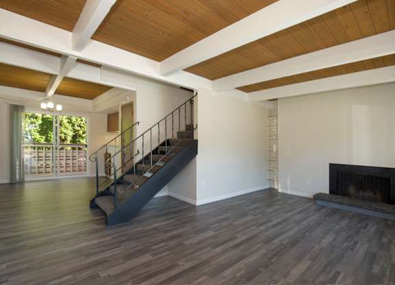 Spacious Living Room with Plank Flooring, Overhead Exposed Beams, Iron Staircase, and Fireplace at Woodlake Townhomes, Washington, 98026