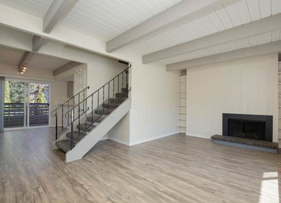Newly Renovated Living Space with Exposed Ceiling Beams, Plank Flooring, a Staircase, and Fireplace at Woodlake Townhomes, Edmonds