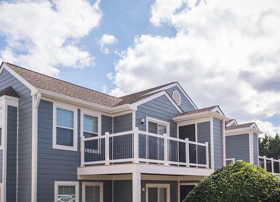 a blue apartment building exterior with large balcony and windows.