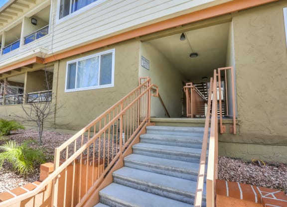 A staircase with a metal railing leads to a balcony on the second floor of a building.