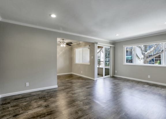 A spacious room with wooden flooring and a ceiling fan.