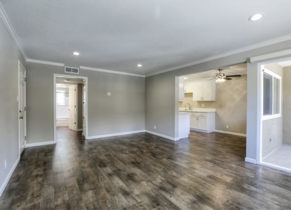 A spacious room with wooden flooring and white walls.