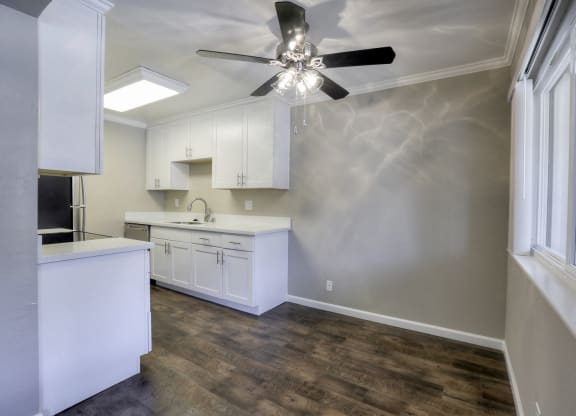 A kitchen with white cabinets and a ceiling fan.