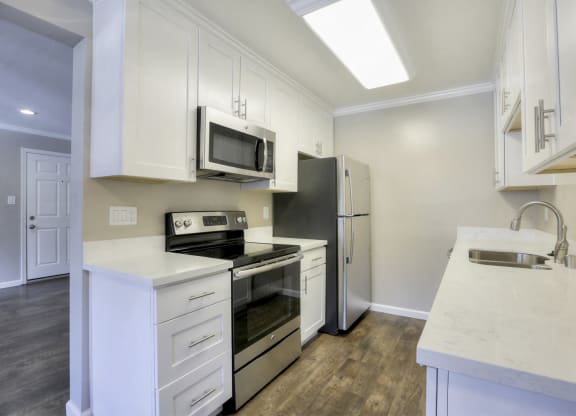 A kitchen with white cabinets and a black refrigerator.