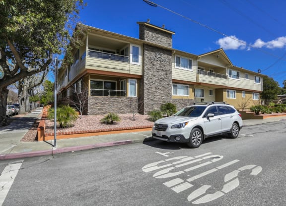 An Apartment building with a white car parked in front of it