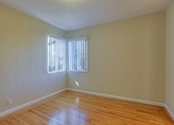 A room with wooden floors and a window with blinds.